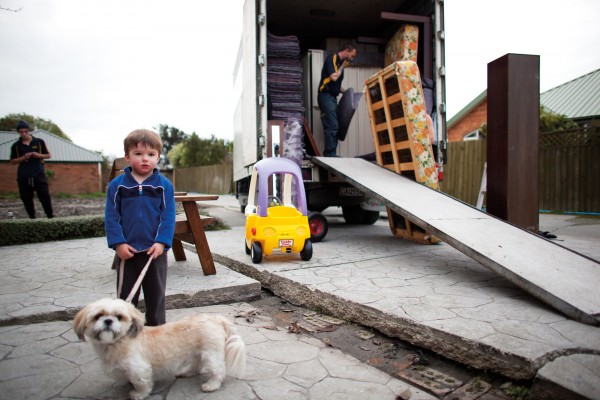 The McGlashon family were hoping their new home would be built before they had to leave their red-zoned neighbourhood in Burwood, but a city-wide backlog in consents and building made this impossible. Now one of the last residents in the street, three-year-old Lucas McGlashon watches on as his family’s belongings are packed up for a temporary move to Kaiapoi. Like many children of the quakes, he has never known stable ground nor concrete without cracks. 