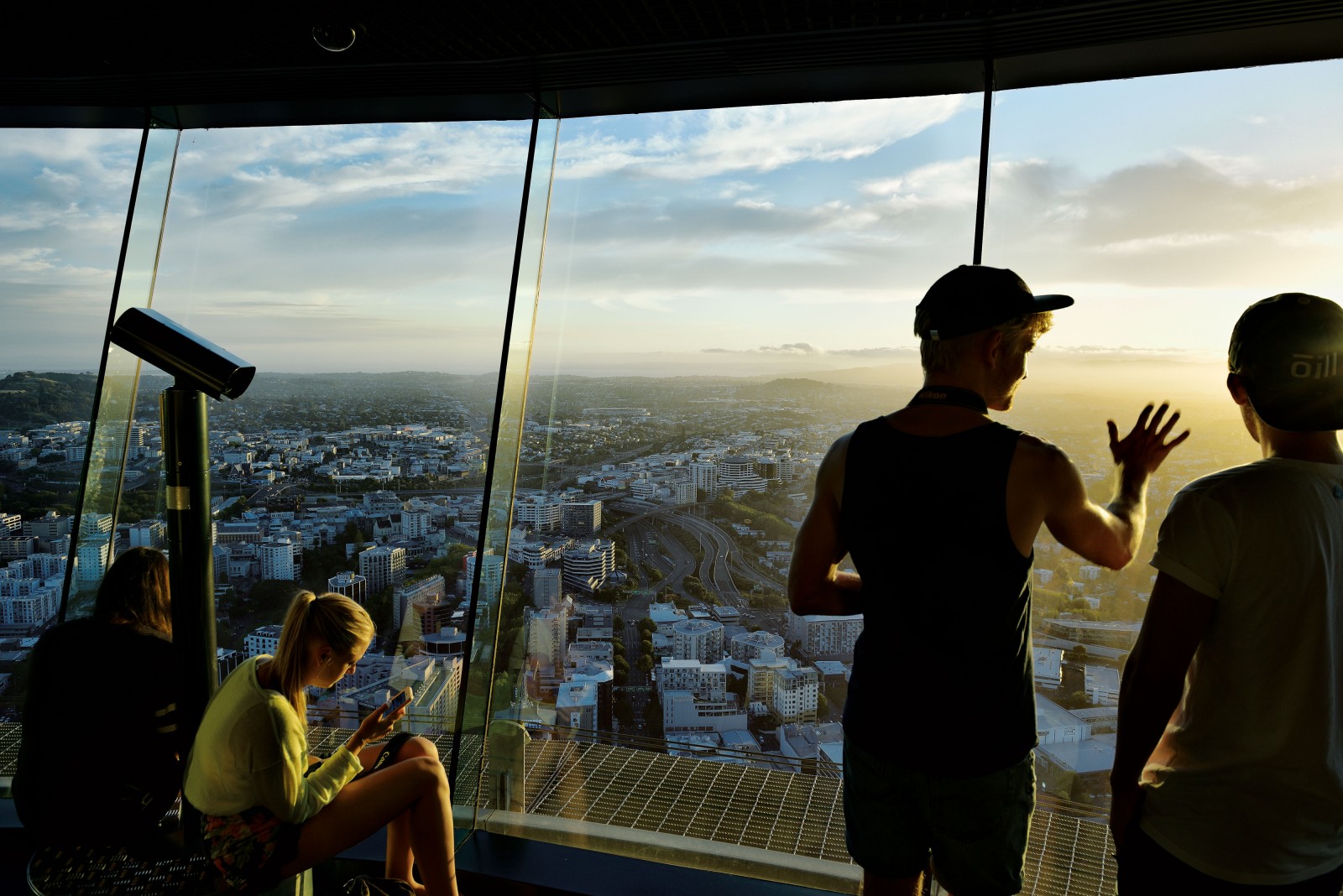 Young Aucklanders look from the Sky Tower toward the sun setting over the western suburbs. As Auckland grows beyond its traditional urban fringe, planners are trying to understand and manage the effects of that growth. Auckland Council’s Alison Reid says that growth projections for the next five to ten years are considered fairly accurate, but at the rate that Auckland is growing and changing, even small variations in the social structure can alter the face of the city’s future. As it is, these students will be supporting an ageing population through their working years, likely more diverse and socially isolated than ever before.