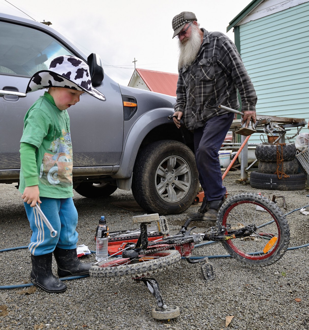 The current president of the Republic of Whangamomona, Murt Kennard, operates the only garage on the Forgotten World Highway. He fixes anything that breaks in the district, including the wheel bearings of this truck. His four-year-old neighbour, Gus Hutchinson, uses the opportunity to effect some repairs on his vehicle too.