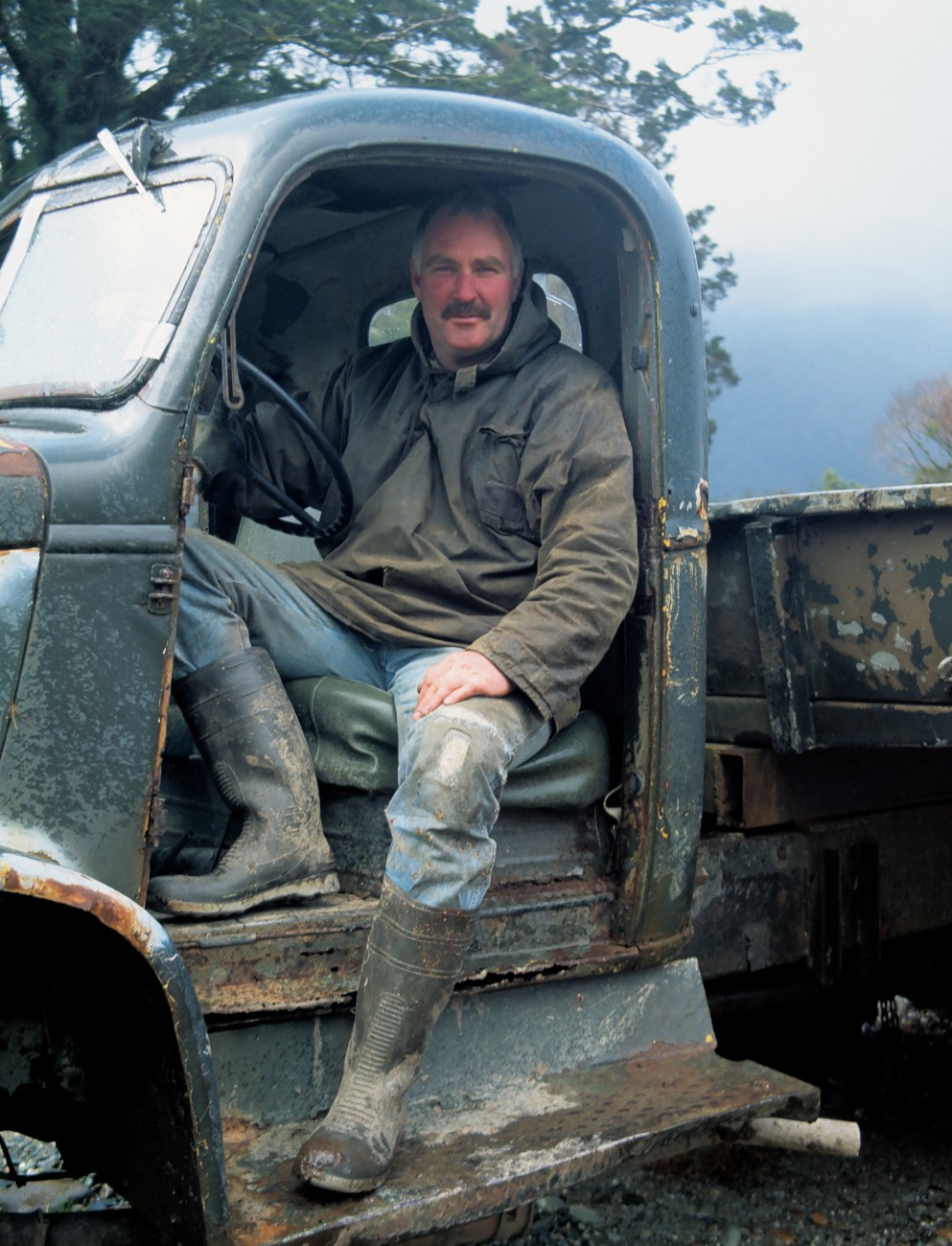 This West Coast truckie may not have a door to keep out the elements, but long gumboots and a parka certainly help.