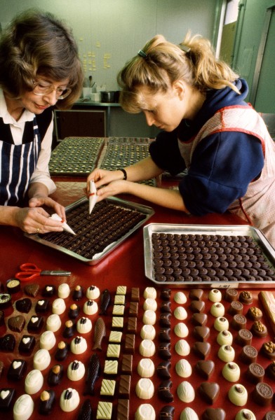 Marjan Hoorens van Heyningen (left) emigrated with her husband Louis eight years ago, tried various jobs. then decided thai what New Zealand needed was good Dutch chocolate. Marjan returned 10 Holland to learn the techniques. and now their Christchurch company produces a wide range of tempting centres. Like many of the more recent immigrants, the van Heyningens moved for the sake of their children. "We wanted them to grow up in a nice, clean environment, and to go 10 a good school where the children don't take drugs." With Marit Veken. Marjan pipes decorations on to a fresh batch of "van H's best".