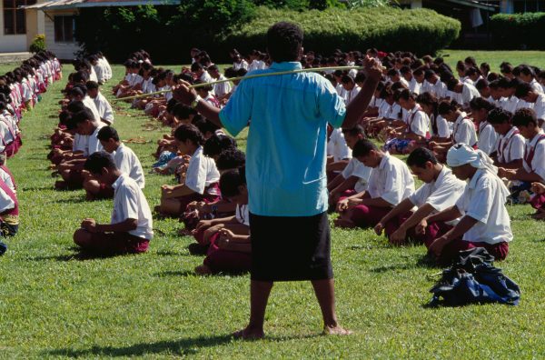 A big stick helps ensure that the pupils of Maluafou College stay in line as they practise a s'asa'a (slap dance) for Western Samoa's Independence Day celebrations. Vigorous corporal punishment is a fact of life for Western Samoan children in school, church and home.