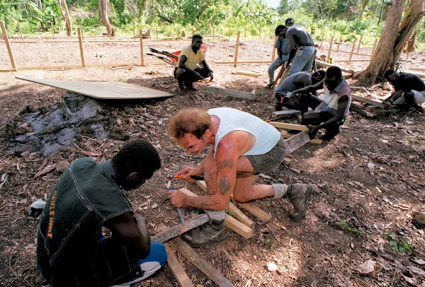 At a VSA school-building project, Kiwi volunteer Roy Bungard helps a former bush fighter with the traditional apprentice chore of building a sawhorse—the first step in learning a new trade, the first step in rebuilding a society.