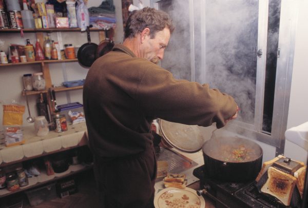 65_MtTarawera_17 Manager Charles Feast cooks a hot meal before heading out for a night's possum shooting on Tarawera's slopes.